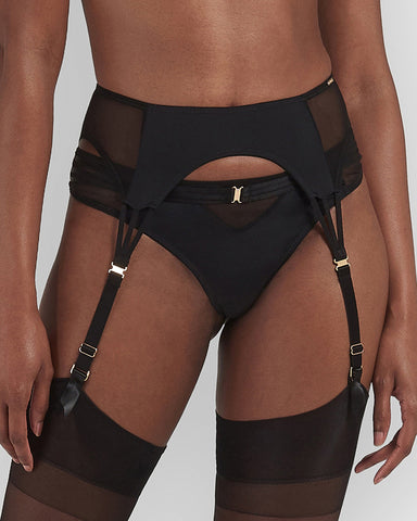 Black suspender belt with black mesh side panels and gold clasp detailing, worn with black stockings and knickers. 